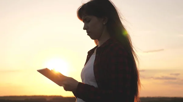 Mujer autónoma que trabaja con Tablet PC, caminando en el parque bajo el sol. Mujer de negocios usando una tableta digital imprime mensajes en la calle de la ciudad. Estudiantes manos táctil pantalla táctil de la tableta. — Foto de Stock