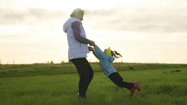 Mama i dziecko bawią się w parku. Zdrowa rodzina i dzieciństwo. Szczęśliwe dziecko bawi się wiosną z matką w locie o zachodzie słońca. Mama okrąża swoje ukochane dziecko rękami, dziecko śmieje się w locie — Zdjęcie stockowe