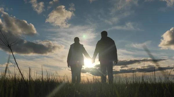 Gente feliz sosteniendo las manos levantan sus manos hacia el cielo en los rayos del atardecer. Trabajo en equipo. Silhouette Parejas alegría juntos al atardecer. Un grupo de personas levanta las manos al sol. empresas conjuntas —  Fotos de Stock