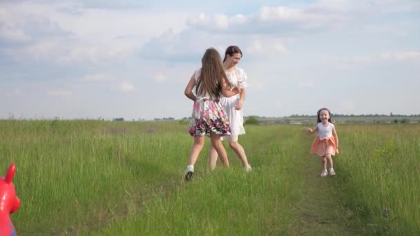 Zusters en mama spelen inhaalslag. Kind loopt vrolijk weg. Gelukkige kinderen, baby en moeder lopen in het voorjaar samen in het park. Gelukkig gezin jogt en speelt op weide in de zomer op groen gras. Teamwork — Stockvideo