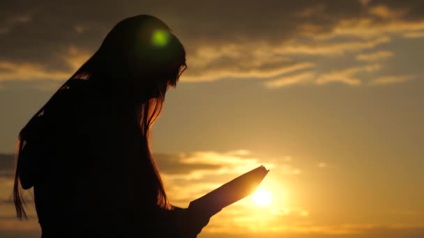 Kobieta czyta książkę w promieniach słońca. Człowiek czyta Biblię na zewnątrz. Człowiek trzyma Biblię w rękach i studiuje Słowo Boże o wschodzie słońca na szczycie góry. Koncepcja samokształcenia, oświecenie — Wideo stockowe