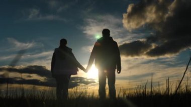 Mutlu insanlar el ele tutuşup gün batımını izler. Takım çalışması. Meditasyon, dua. Siluet Çiftler gün batımında birlikte sevinirler. Bir grup insan güneşe doğru el ele tutuşuyor. Güven ve sevgi