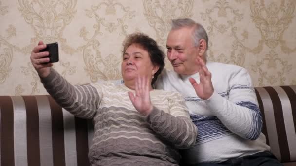 Un anziano, coppia sposata ylogger online scattare video e foto su smartphone moderno. Una famiglia felice. Le coppie sposate di mezza età felici vengono fotografate su uno smartphone, scattano selfie insieme a casa — Video Stock