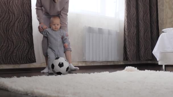 Mor och barn, son spelar fotboll i rummet, sparkar fotboll. Barnet njuter av att leka med sin mamma hemma. Lycklig, hälsosam, sportig familj. Utveckla ditt barn genom aktiva sportspel — Stockvideo
