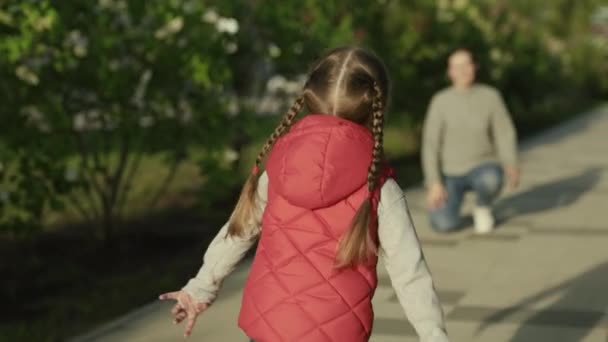 La familia feliz, el niño, la hija corre a la mamá y la abraza en el parque en la calle en primavera.La infancia despreocupada, la carrera alegre del bebé a la madre. Pequeño niño juega alegremente en verano en la calle con sus padres — Vídeos de Stock