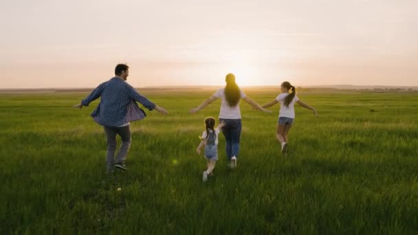 Glückliches Familienteam, das zusammen läuft, hebt die Hände wie ein Flugzeug. Glückliche kleine Tochter, rennt und fängt Mama und Papa. Teamarbeit der Menschen. Gruppe von Menschen unterschiedlichen Alters bei Sonnenuntergang. Glückliches Familienspiel — Stockvideo