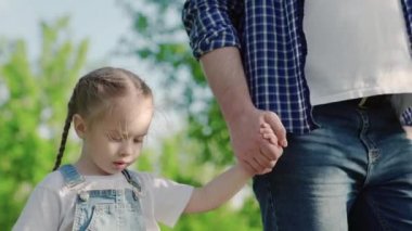 Parktaki insanlar. Gün batımında mutlu aile silueti yürüyüşü. Anne, baba ve kızları parkta el ele yürüyorlar. Mutlu aile çocuğu hayali konsepti. Aileler ve eğlenceli çocuklar siluete geri dönüyorlar.