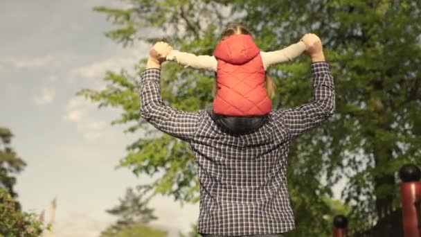 O pai e a filha estão a brincar no parque. Uma família feliz. Um pai e uma criança, junto com sua filha, sonham com o voo, a família caminha pela rua ao sol. Feliz família e união. Fim de semana na natureza — Vídeo de Stock