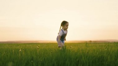 Doğadaki çocuklar için aktif oyunlar. Mutlu çocuk, kız parkta yeşil çimlere gider, tarlada çiçek toplar, Kid gülümser. Çocukluk rüyası. Kızım dışarıda çok eğleniyor. Mutlu aile, çocukluk