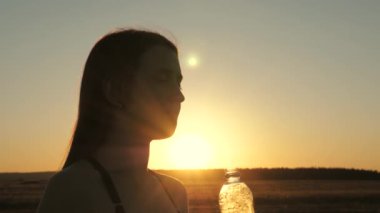 Genç bayan dışarıda çalıştıktan sonra su içer. Yaz parkında spor. Kız bahar aylarında parkta idmandan sonra şişeden temiz maden suyu içiyor..