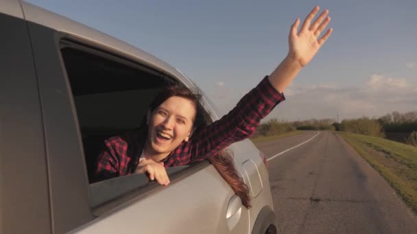 Darmowe szczęśliwy beztroski nastolatek dziewczyna patrząc przez okno samochodu radośnie machając ręką. Młoda kobieta podróżująca samochodem, siedząca na tylnym siedzeniu, świecąca słońcem, wiatrem ręką. Turystyka, podróże — Wideo stockowe
