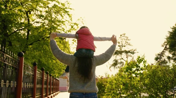 Mutter und Tochter spielen im Park. Eine glückliche Familie. Mutter und Kind träumen mit ihrer Tochter von der Flucht, die Familie läuft in der Sonne die Straße entlang. Glückliche Familie und Zweisamkeit. Wochenende in der Natur — Stockfoto