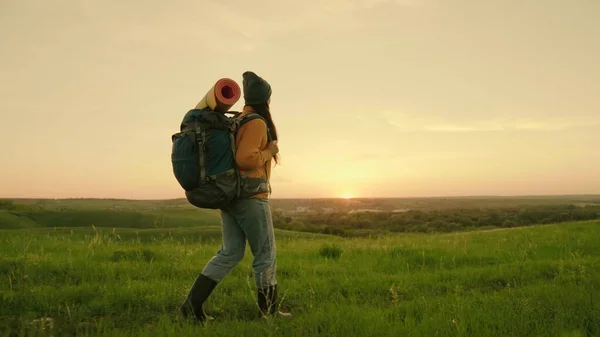 Femme voyageuse libre marchant dans la prairie en été. Fille voyageur voyage le long du sommet de la colline verte au soleil, méditation, écotourisme, randonnée. Une jeune femme caucasienne active avec sac à dos part en randonnée — Photo