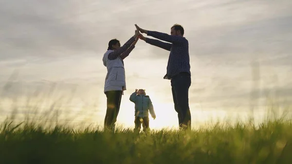 Glad familj leker med liten dotter, familj symbol hemma i solen. Mamma, pappa och de skildrar med händerna tak över huvudet. Dröm om ett delat hem. Husbyggare — Stockfoto