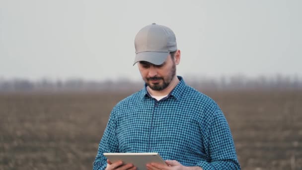 男性農家は、カメラの笑顔を見てデジタルコンピュータで分野で働いています。彼の手にタブレットを持つ農学者。環境に優しい農業。現代のデジタル技術、農業 — ストック動画