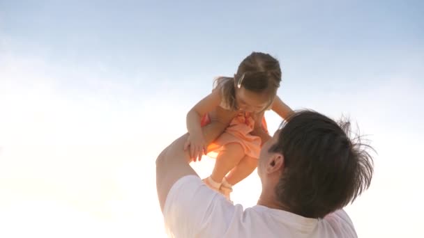 Otec a malé dítě si hrají, smějí se a objímají v letním parku. Šťastná rodina. Táta drží šťastnou dceru v náručí a zvedá ji. Užij si rodinnou cestu. Dítě je v náručí rodičů. — Stock video