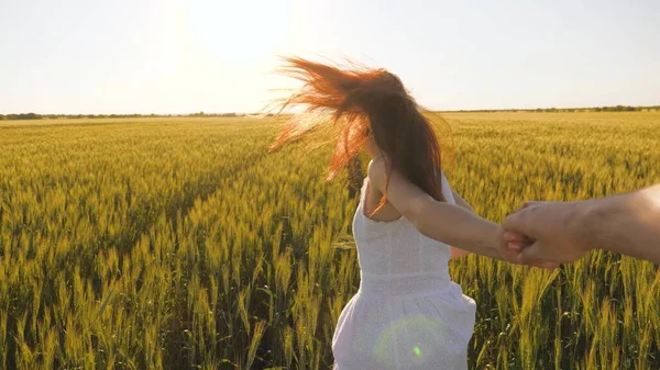Libre relation romantique de couple amoureux. Une femme insouciante et l'homme courent ensemble à travers le champ de blé tenant la main au soleil d'été. Une famille d'agriculteurs. Une fille et un gars voyagent à travers le champ de blé. — Photo