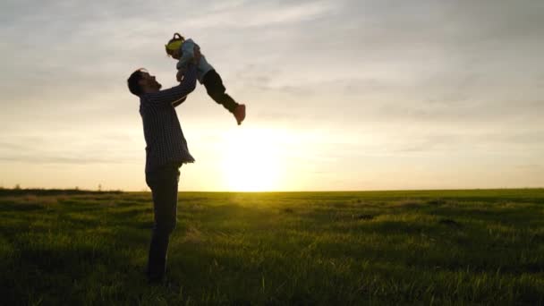 Papá lanza a su hija feliz al cielo azul en rayos de sol. Padre e hijo juegan, se ríen y se abrazan juntos. La familia feliz viaja. Bebé en brazos de padre. Papá día libre. Concepto de familia feliz — Vídeos de Stock