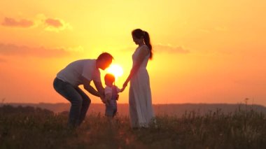 Mutlu aile gün batımında yaz parkında oynuyor. Baba sevgili kızını kusar, mutlu çocuk güler ve sevinir, babasına dışarıda sarılır. Çocuk, baba, anne. Baba kız oynuyor, uçma hayalleri kuruyor.