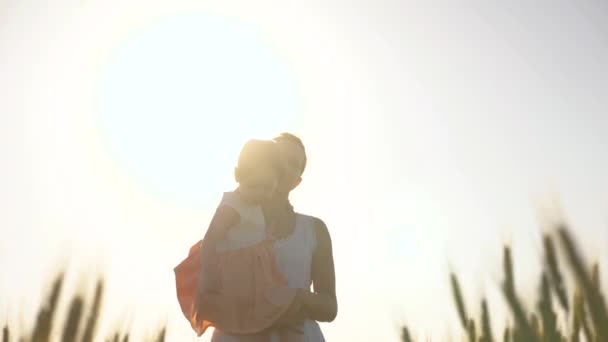 O bebé está nos braços das mães. Mãe e filhinha estão andando em um campo de trigo verde, abraçando e beijando. Uma criança e mãe estão andando no campo de trigo. Feliz viagem em família. Mulher agricultora e criança no campo — Vídeo de Stock