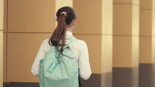 Student teenager walking along the city street. A teenage girl hurries to class. A schoolgirl with a backpack walks down the street to school, beautiful young student goes to class. Education concept. —  Fotos de Stock