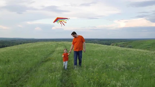 Happy family, daughter and dad raise a kite into the sky. Family weekend play outdoors. Child and dad play together with kites against the sky in the park. The concept of healthy children and parents. — Fotografia de Stock