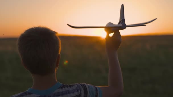 Le gamin court avec un avion jouet. Joyeux enfant, garçon, cours sur le soleil en jouant avec un avion jouet sur le terrain d'été. Une famille heureuse joue dans le parc. Fils rêve de voler. Enfant insouciant jouant à l'extérieur — Video