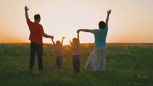 Glad familj som håller varandra i händerna räcker upp handen. Lagarbete av människor. Familjeglädje. En grupp människor i olika åldrar i solnedgången höjer sina händer mot himlen. Partnerskap och hjälp affärsidé. — Stockfoto