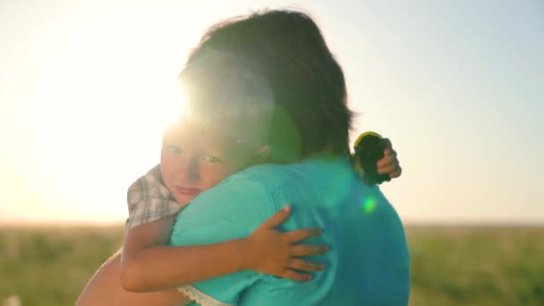 Happy son hugs his mom in the summer park in the sunshine. Cute affectionate little boy hugging a kind mother. Adorable little son hugging mommy, enjoying family happiness. Family walking in nature — Stock Video