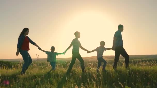 Gelukkig familie team lopen samen hand in hand in de zon. Gelukkige kinderen, zonen, hou mama en papa bij de hand. Teamwork van mensen. Een groep mensen van verschillende leeftijden bij zonsondergang. Gelukkige familie spelen — Stockvideo