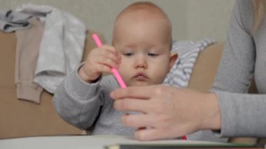 Küçük bir kız çocuğu, sarı kalemle kağıdın üzerine resim çiziyor, annesinin yanında küçük bir kız. Mutlu bir aile ve çocuk. Evlat, çocuk renkli kalemlerle resim çiziyor, çocuk evde annesiyle birlikte.