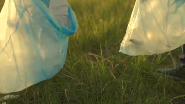 Dobrovolník člověk se zabývá úklidem plastového odpadu v parku na trávě. Dělnická ruka zvedne plastikovou láhev z trávy do alugy. Šetrná k životnímu prostředí. Lidské znečištění přírody. — Stock video