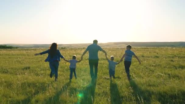 Fils heureux, enfants, maman et papa courent, jouent, se réjouissent, profiter de la nature en été. Bonne équipe familiale, courez ensemble en vous tenant la main dans le parc. Le travail d'équipe des gens. Un groupe de personnes d'âges différents au coucher du soleil. — Video