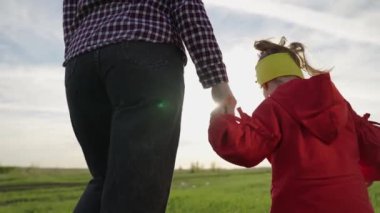 Tasasız kız ve anne birlikte sahada yürüyorlar. Mutlu aile çocuğu ve annesi parkta el ele tutuşuyorlar. Küçük kız annesinin elini tutuyor. Sağlıklı bir çocukluk ailesi kavramı.