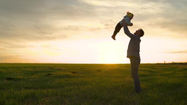 Dziecko w ramionach rodzica. Tata rzuca swoją szczęśliwą córkę w błękitne niebo w promieniach słońca. Ojciec i małe dziecko bawią się, śmieją się i przytulają. Szczęśliwej podróży rodzinnej. Dzień wolny od taty. Pojęcie szczęśliwej rodziny — Wideo stockowe