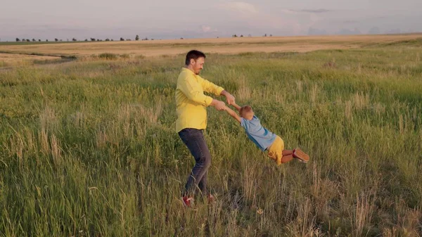 Papa entoure les bras de son fils heureux dans le parc au soleil. Père, petit enfant jouent, rient et se réjouissent ensemble. Joyeux voyage en famille. Le bébé est dans les bras des parents. Les pères sont en congé. Concept de famille heureuse — Photo