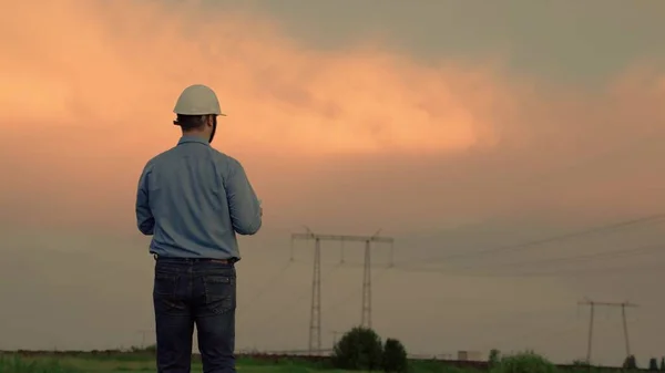 Engenheiro elétrico moderno, trabalhando em tablet digital. Um engenheiro elétrico trabalha com tablet de computador, trabalha com eletricidade ao lado de uma torre elétrica. Indústria de tecnologias de negócios de energia. — Fotografia de Stock