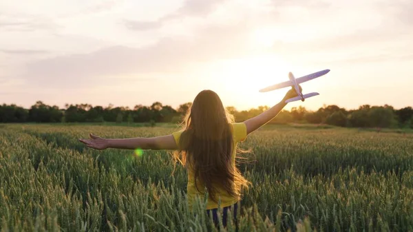 Flicka drömmer om att flyga. Barnflicka springer med leksaksflygplan på vetefält. Glada barn som springer i solen, leker med leksaksflygplan på sommaren vid solnedgången. Lycklig familj. bekymmersfritt barn leker utomhus — Stockfoto
