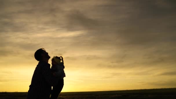 Silhouette Dad wirft seine glückliche Tochter in den blauen Himmel. Glücklicher Familienurlaub. Vater und Kind spielen, lachen, umarmen sich. Angenehme Familienreisen. Baby liegt in den Armen der Eltern. Vatertag frei — Stockvideo