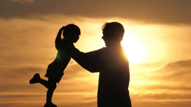 Babam sevgili mutlu kızını kollarının arasına alıyor. Gün batımında birlikte oynayan baba ve çocuğun silueti. Baba ve küçük çocuk, parkta güneş altında oynuyorlar. Aile tatilde. Çocukluk