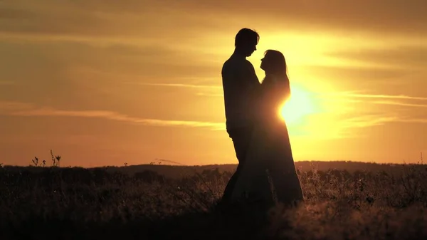 Silhouette de jeunes mariés heureux dansant au coucher du soleil. Heureux homme danse et tourne avec sa femme bien-aimée dans le parc d'été. Guy et fille dansent sous les rayons lumineux du soleil dans le champ. Des gens libres. — Photo