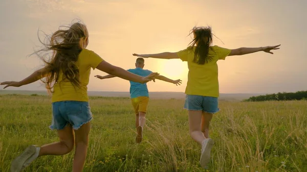 Groupe d'adolescents jouant dans le parc au soleil, plaisir de vacances bonheur. Joyeux famille, enfants, fils et filles qui courent ensemble dans le parc au coucher du soleil. Bonne famille. Amis rêve de piloter un avion — Photo