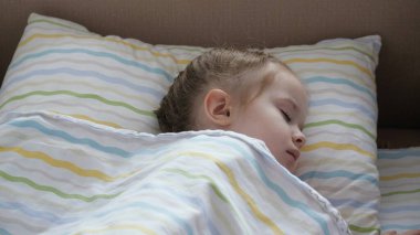 Yatağındaki kreşte uyuyan tatlı bir bebek. Mutlu bebek bebek bebek yatağında uyur ve gülümser. Annem yorgun kızını yatağına yatırdı. Mutlu aile ve çocukluk kavramı. Sağlıklı çocuklar.