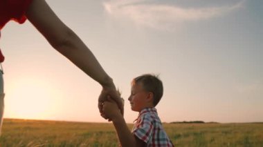 Anne ve oğul parkta el ele tutuşup birlikte yürüyor ve oynuyorlar. Çocuğun elinde pikap oyuncağı var. Parktaki insanlar. Mutlu aile yürüyüşleri, çocuk, çocuk, anne dışarıda. Ebeveynler, çocuklar, rüya, çocukluk