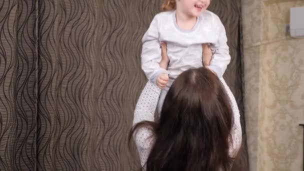 Happy family, child, daughter, mom, play paddle together in the room. A young mother throws up her little daughter, the baby rejoices and laughs. The family laughs while playing. Family home games — Vídeo de Stock