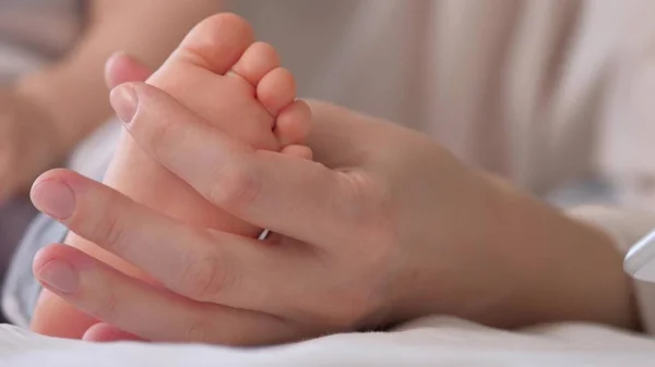 Baby voeten in moeders handen. Gezonde baby en mama. Baby benen, mama zal baby knuffelen met haar handen. Gelukkige moeder en haar baby spelen samen. Een gelukkig gezin. Gelukkige kinderopvang — Stockfoto