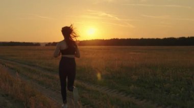 Antrenman koşusu. Özgür genç bir kadın yazın şafak vakti parkta koşar kulaklıkla müzik dinler. Sağlıklı koşu ve açık hava egzersiz konsepti. İnternet olmadan müzik dinlemek ve spor yapmak.