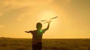 Mutlu çocuk, çocuk, yaz sahasında oyuncak bir uçakla oynarken güneşte koşar. Çocuk oyuncak bir uçakla koşuyor. Mutlu aile parkta oynuyor. Oğlu uçmayı hayal ediyor. Tasasız çocuk dışarıda oynuyor.