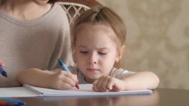 Anne, çocuk, kız birlikte evde çizim yapıyorlar. Küçük kız, anne, hayal gücünü kullanarak renkli kalemlerle resim çiziyor, evde sanat yaratıyor, sanatçı olma hayalleri kuruyor. Aile eğitimi