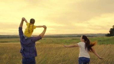 Mutlu aile yazın gün batımında el ele tutuşarak parkta koşar. Aile kutlaması. Anne, baba ve kız sahada oynuyorlar, çocuk babalarının omuzlarında oturuyor, uçma hayalleri kuruyor. Takım çalışması. Mutlu sağlıklı bir çocukluk